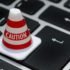 photo of a caution cone on a computer keyboard symbolizing being careful when Buying Fishing & Hunting Permits Online